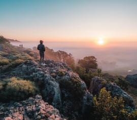 Personne contemplant le soleil au loin
